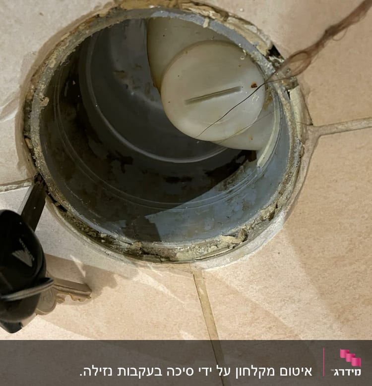 פתח ניקוז עם מכסה פלסטיק ומפתח על הרצפה
